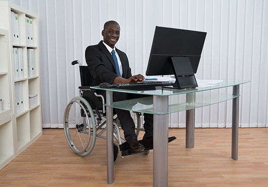 A man sitting in a wheelchair behind his desk